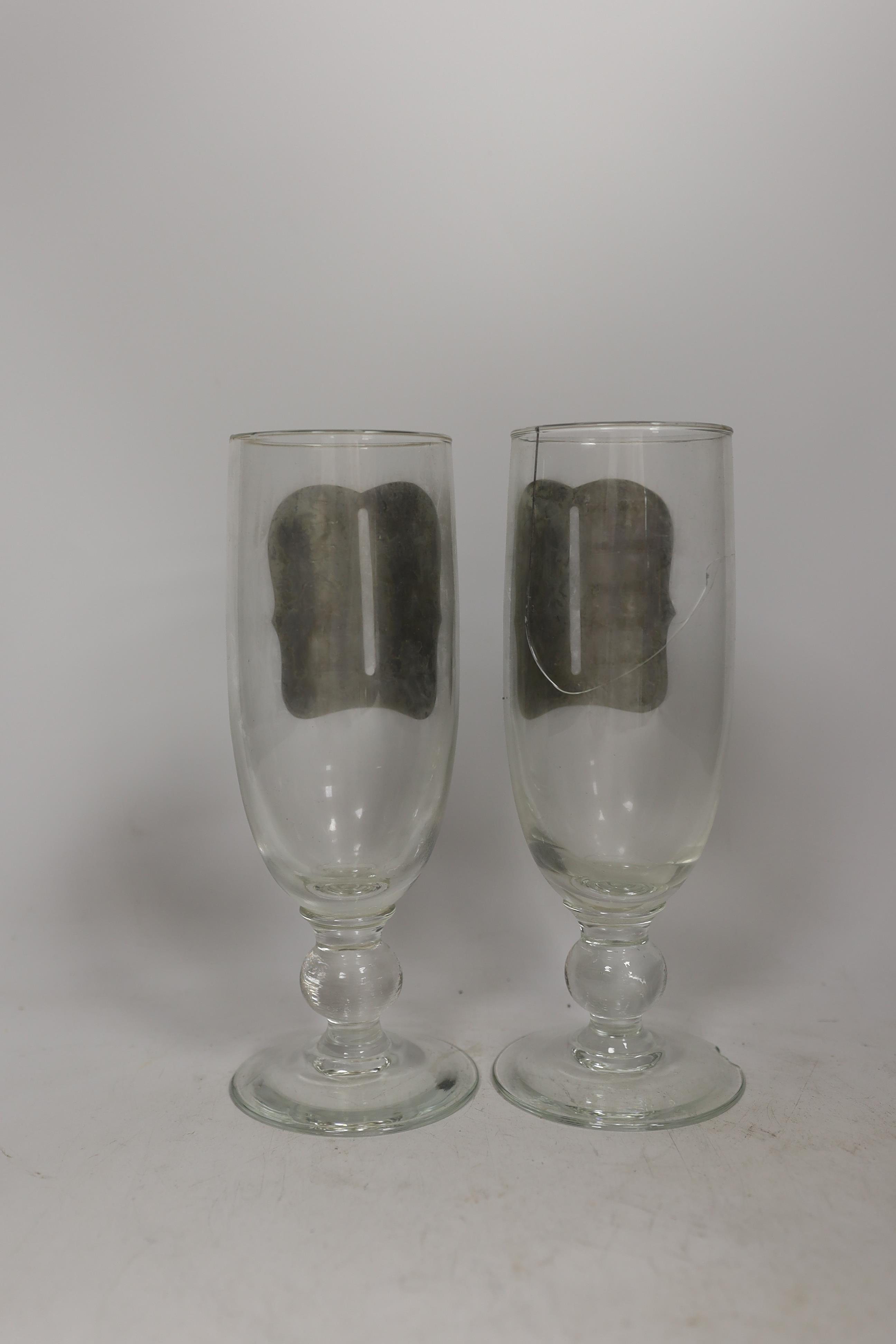 A pair of early 20th century drinking glasses with pewter measures, in a wooden case, one cracked and chipped, 24cm